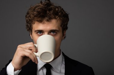 gri arka plan üzerine bir fincan ile takım elbiseli şık adam