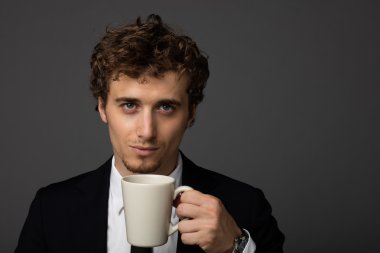 gri arka plan üzerine bir fincan ile takım elbiseli şık adam