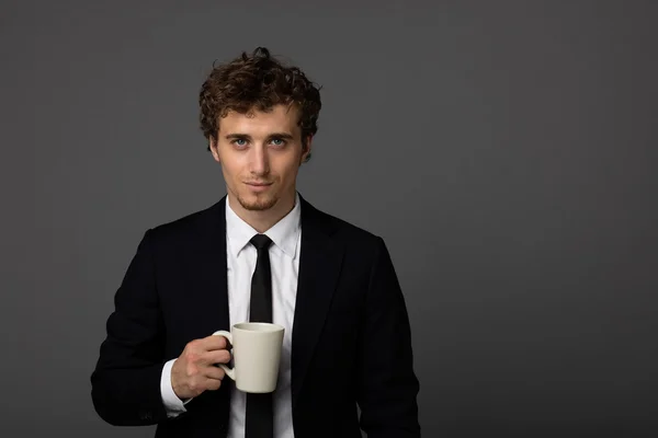 Élégant homme en costume avec une tasse sur fond gris — Photo