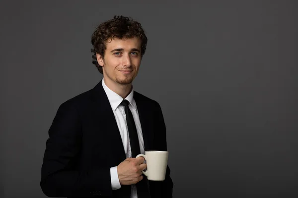 Hombre elegante en traje con una taza sobre fondo gris — Foto de Stock