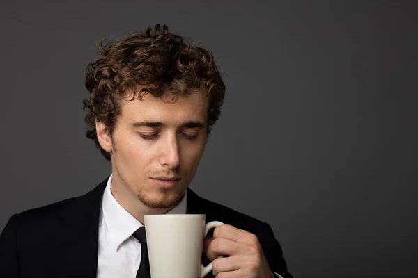 Homem elegante em terno com uma xícara no fundo cinza — Fotografia de Stock