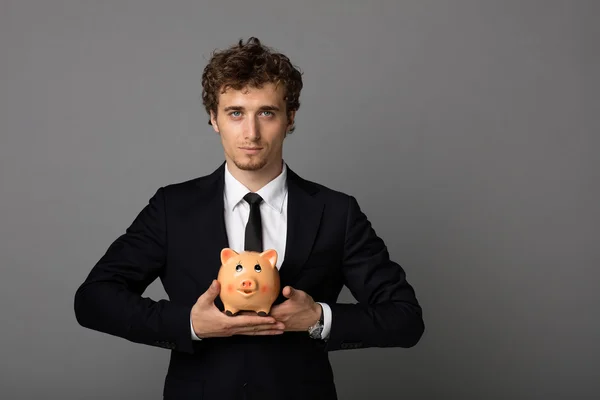 Hombre elegante con piggybank sobre fondo gris — Foto de Stock