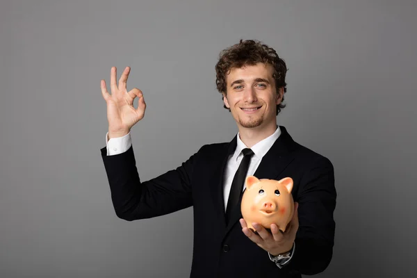 Homem elegante com piggybank no fundo cinza — Fotografia de Stock