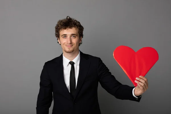 Handsome man in shuit holding a heart in hands — Stock Photo, Image