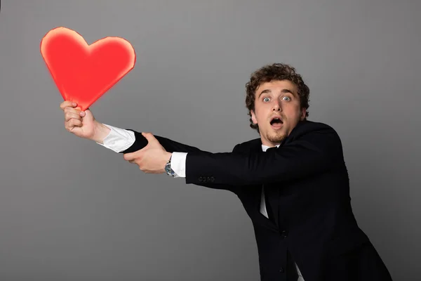 Handsome man in shuit holding a heart in hands — Stock Photo, Image