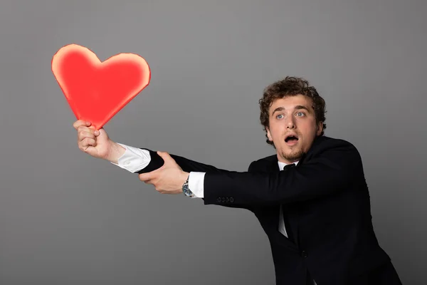 Handsome man in shuit holding a heart in hands — Stock Photo, Image