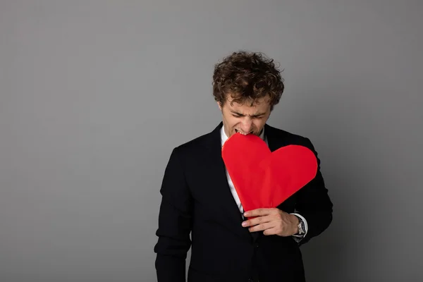 Handsome man in shuit holding a heart in hands — Stock Photo, Image