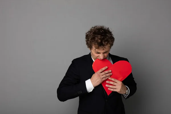 Handsome man in shuit holding a heart in hands — Stock Photo, Image