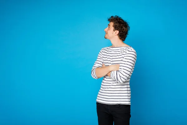 Junger lockiger Mann auf blauem Hintergrund — Stockfoto
