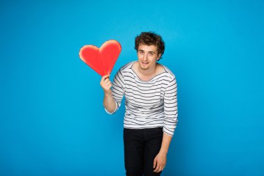 kıvırcık delikanlı ile mavi arka plan üzerinde kırmızı kalp
