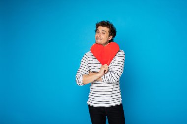 kıvırcık delikanlı ile mavi arka plan üzerinde kırmızı kalp