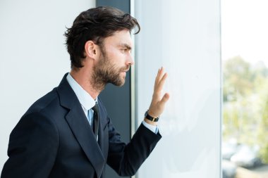 büyük bir pencere yanında duran işadamı