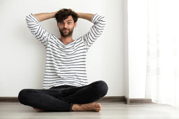 Handsome man in stripes sitting down on the floor — Stock Photo, Image