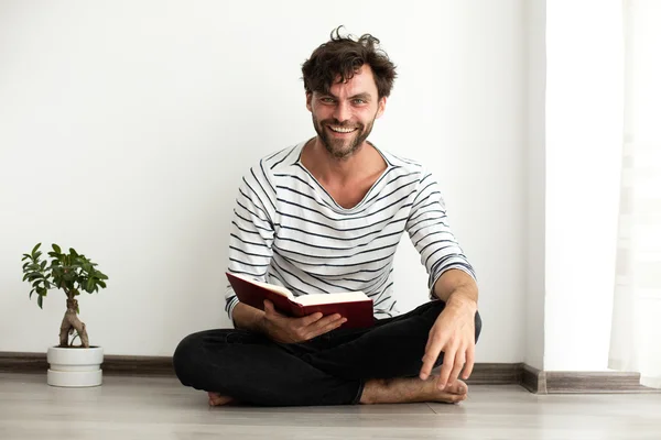 Hombre leyendo un libro y de pie en el suelo — Foto de Stock