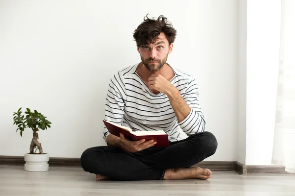 Hombre leyendo un libro y de pie en el suelo — Foto de Stock