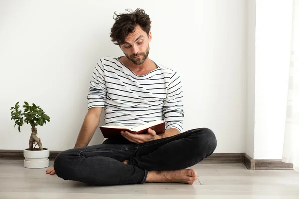 Hombre leyendo un libro y de pie en el suelo — Foto de Stock