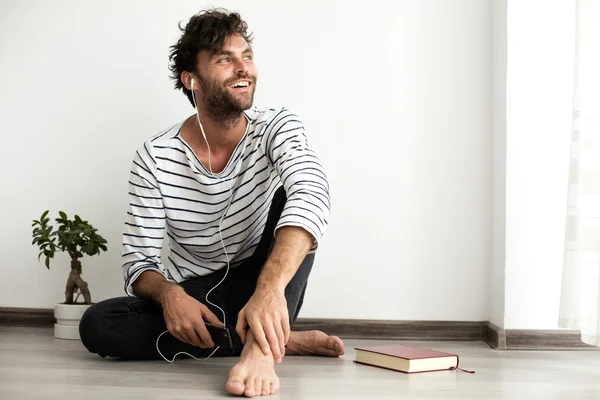 Junger Mann auf dem Boden sitzend mit Headsets in den Ohren und — Stockfoto