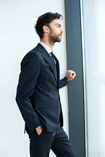 Businessman standing next to a big window — Stock Photo, Image