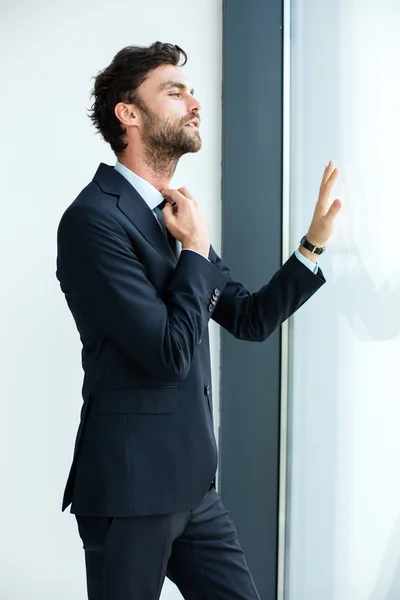 Businessman standing next to a big window — Stock Photo, Image