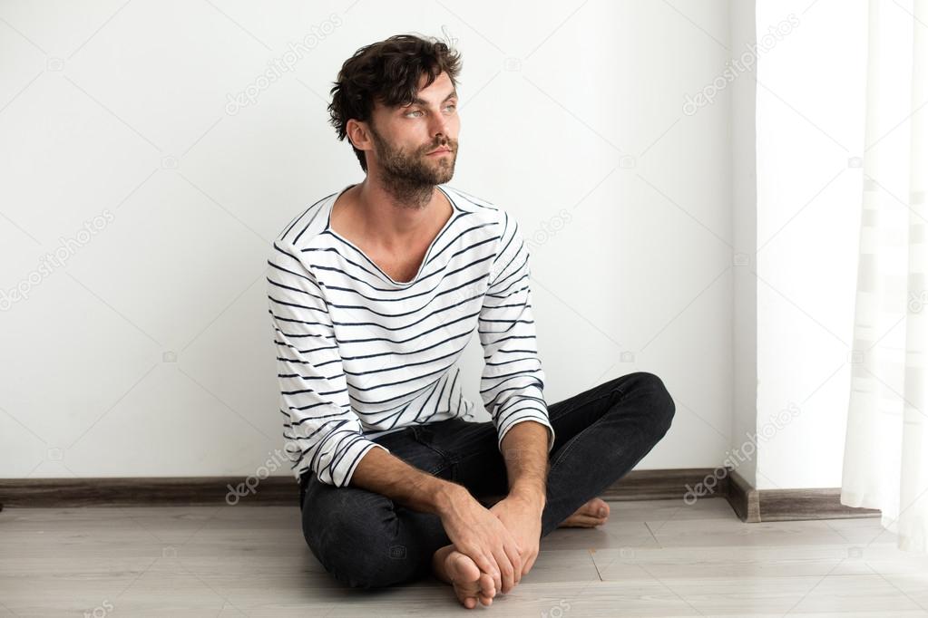 Handsome man in stripes sitting down on the floor