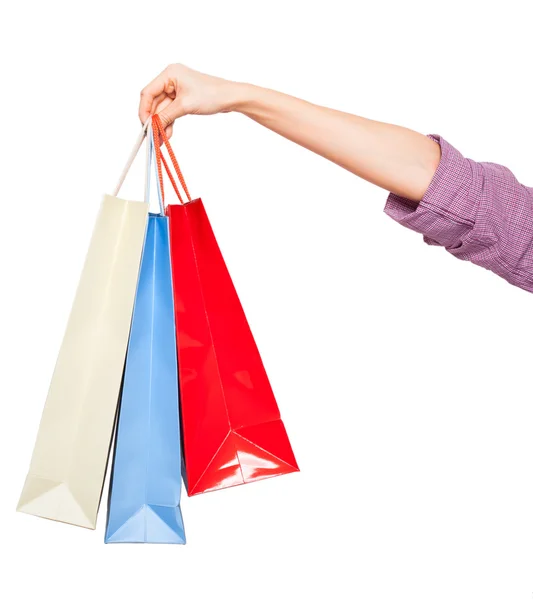 Mãos segurando sacos de compras coloridas no fundo branco — Fotografia de Stock