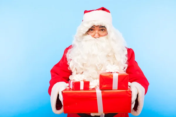 Санта-Клаус з подарунками на руках на синьому фоні — стокове фото