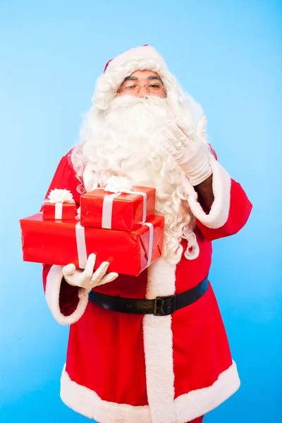 Santa claus avec des cadeaux sur les mains sur fond bleu — Photo
