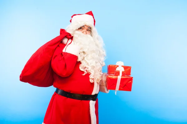 Weihnachtsmann mit Geschenken auf Händen auf blauem Hintergrund — Stockfoto