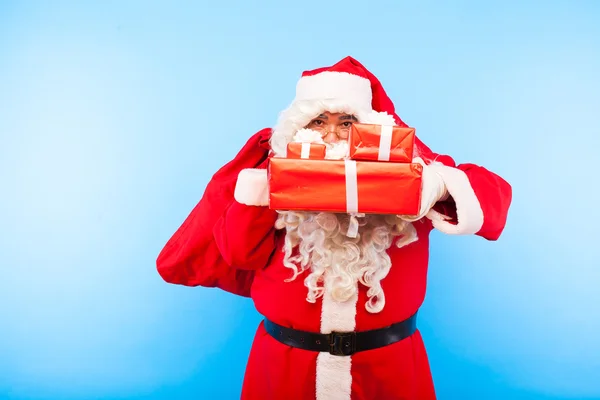 Kerstman met giften op handen op blauwe achtergrond — Stockfoto