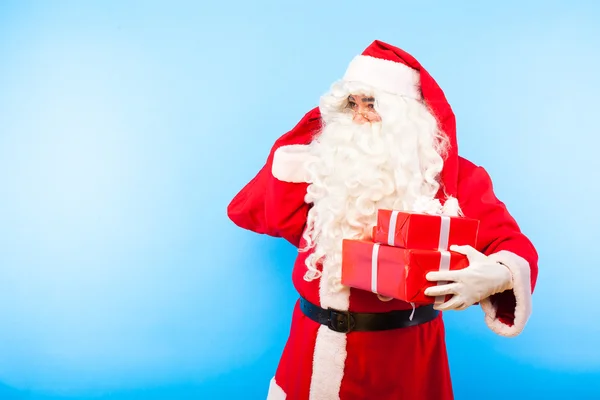 Santa claus avec des cadeaux sur les mains sur fond bleu — Photo