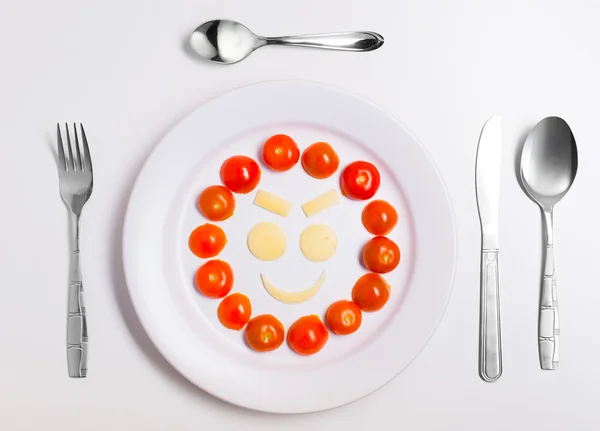 Piatto con emoticon divertenti a base di cibo con posate su bianco — Foto Stock