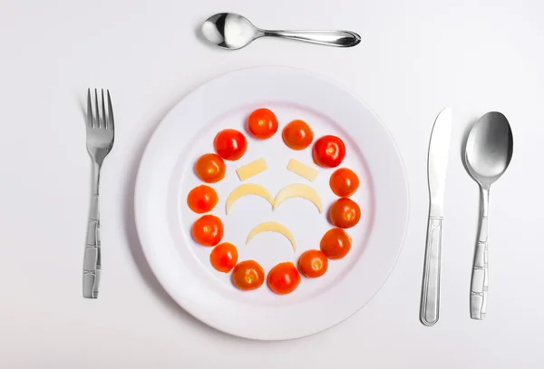 Assiette avec émoticônes drôles fabriqués à partir de nourriture avec couverts sur blanc — Photo