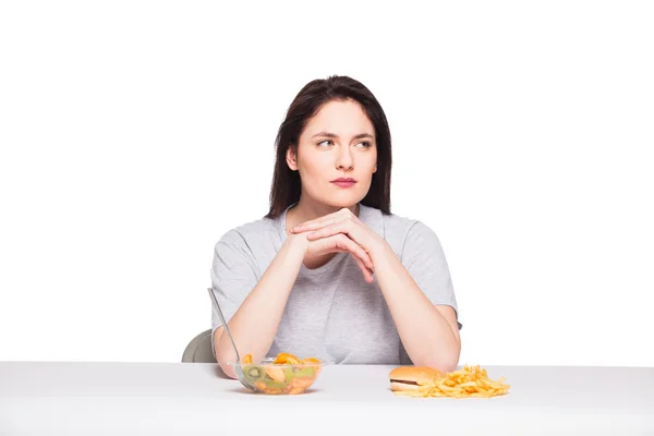 Picture of woman with fruits and hamburger in front on white bac — Stock Photo, Image
