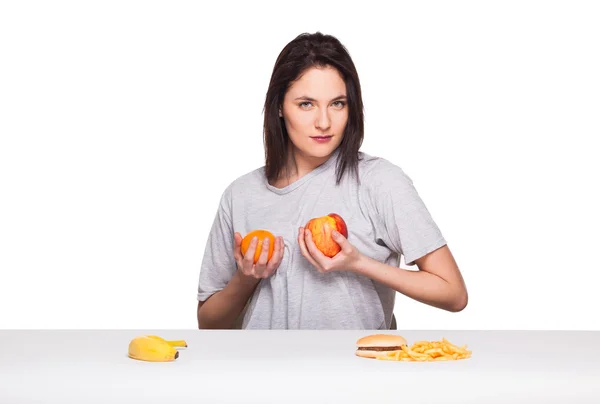 Imagen de la mujer con frutas y hamburguesa en frente en bac blanco — Foto de Stock