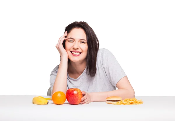 Picture of woman with fruits and hamburger in front on white bac — Stock Photo, Image