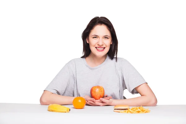 Foto van vrouw met vruchten en hamburger vooraan op witte bac — Stockfoto