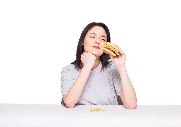 Young woman eating hamburger isolated on white — Stock Photo, Image