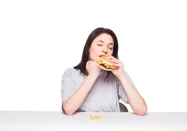 Молода жінка їсть гамбургер ізольовано на білому — стокове фото