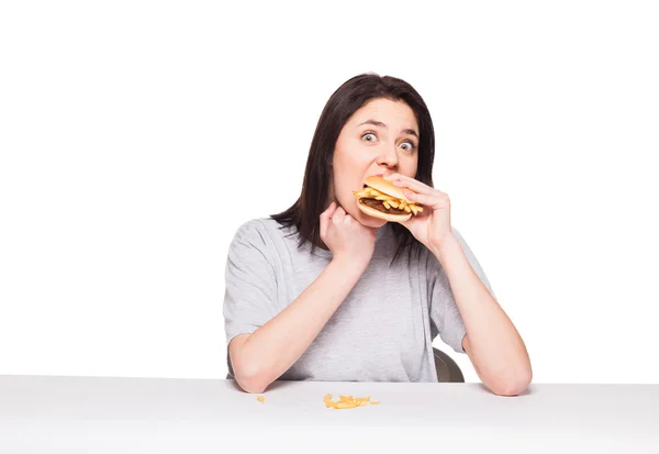 白で隔離ハンバーガーを食べる若い女性 — ストック写真