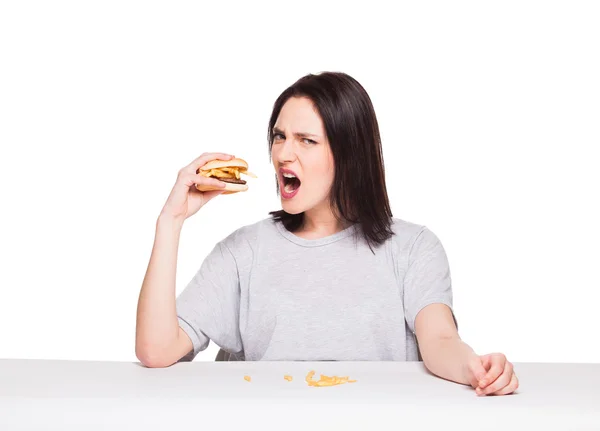 Νεαρή γυναίκα τρώει χάμπουργκερ που απομονώνονται σε λευκό — Φωτογραφία Αρχείου