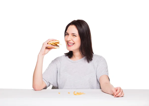 Νεαρή γυναίκα τρώει χάμπουργκερ που απομονώνονται σε λευκό — Φωτογραφία Αρχείου