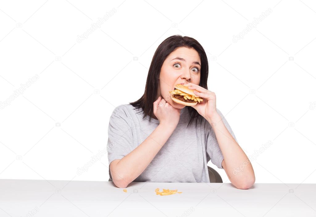 young woman eating hamburger isolated on white