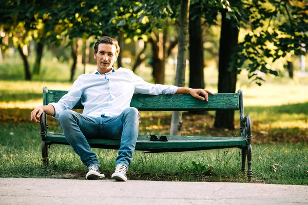 Szép felnőtt ember ül a padon — Stock Fotó