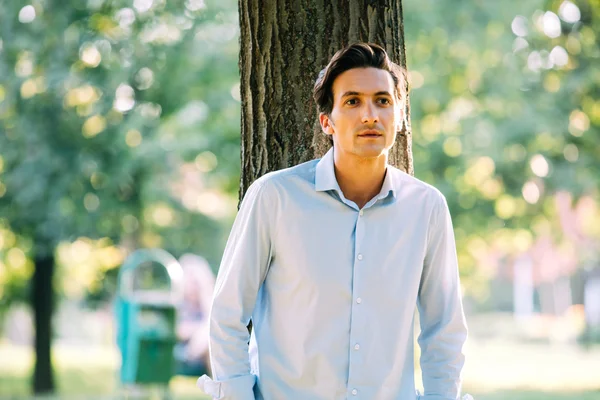 Handsome adult man leaning on a tree — Stockfoto