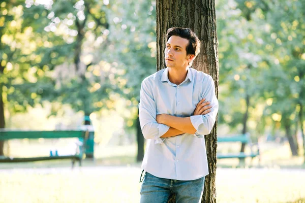 Handsome adult man leaning on a tree — Stockfoto