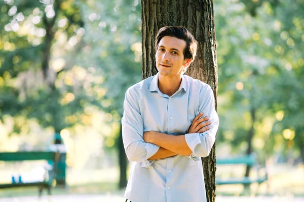 Handsome adult man leaning on a tree — Stockfoto