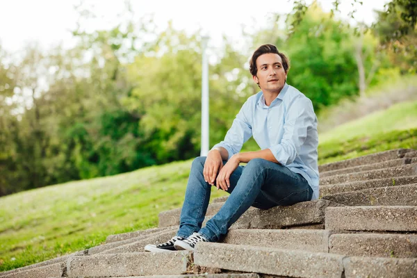 Vuxen man sitter på trappan i en park — Stockfoto