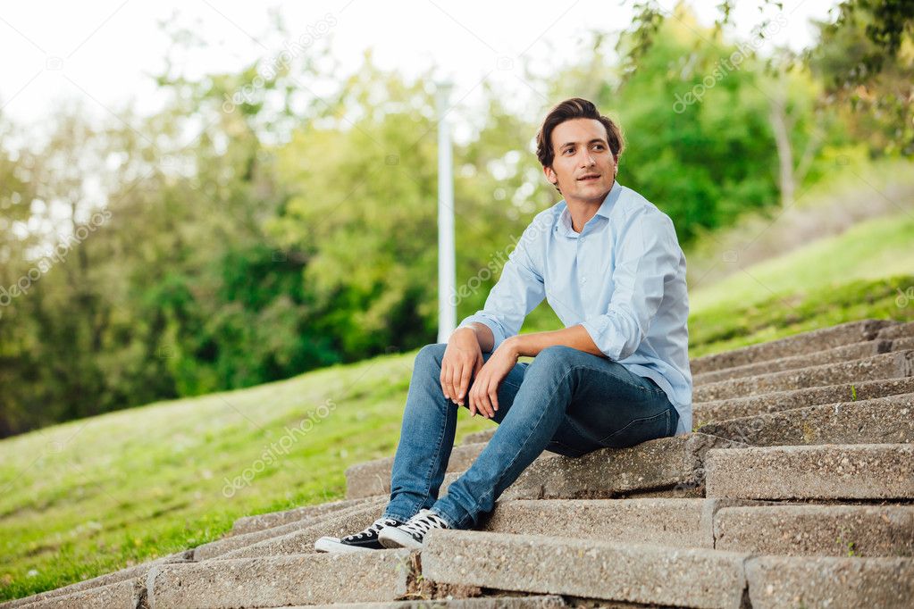 adult man sitting on stairs in a park
