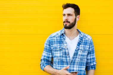 Sarı duvar kulaklıklarla yakışıklı delikanlı