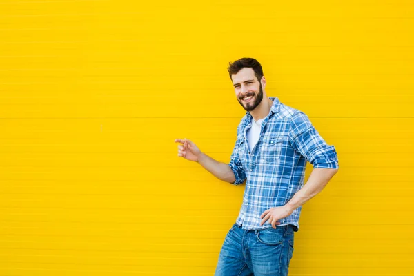 Jovem homem feliz de pé contra uma parede amarela — Fotografia de Stock